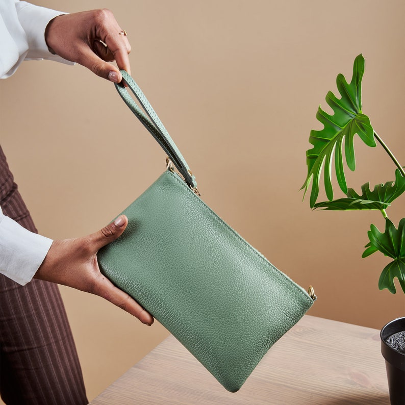 a person holding a green purse next to a potted plant