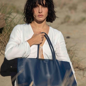 a woman carrying a blue purse on the beach