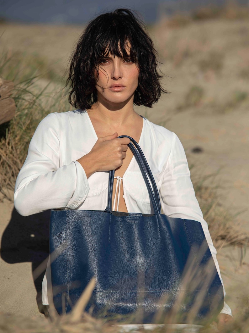 a woman carrying a blue purse on the beach