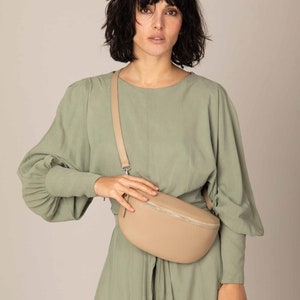 a woman in a green dress holding a beige purse