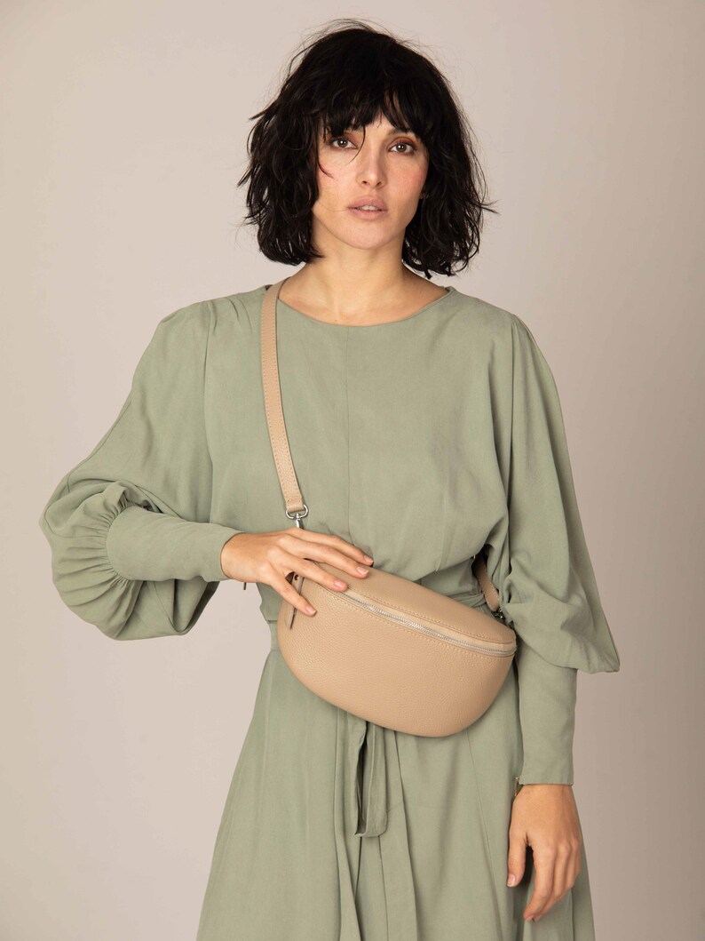 a woman in a green dress holding a beige purse