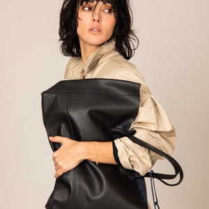 a woman is holding a black leather bag