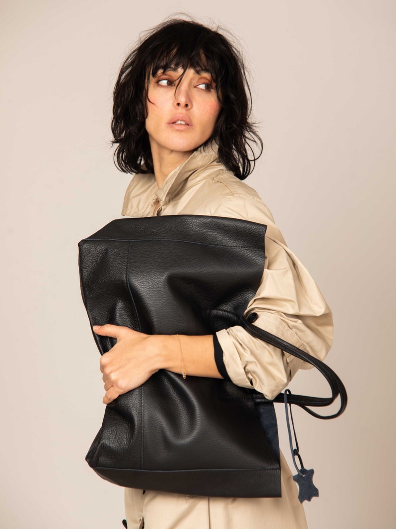 a woman is holding a black leather bag