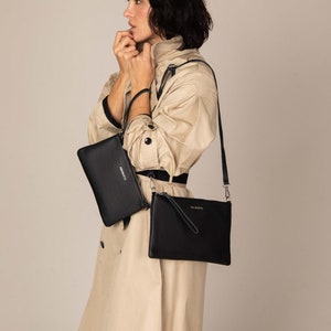 a woman in a trench coat holding a black purse