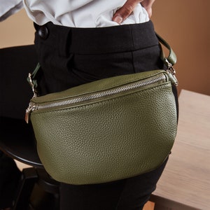 a woman is holding a green leather purse