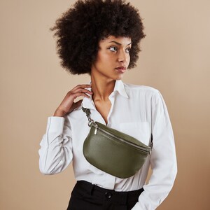 a woman in a white shirt is holding a green purse