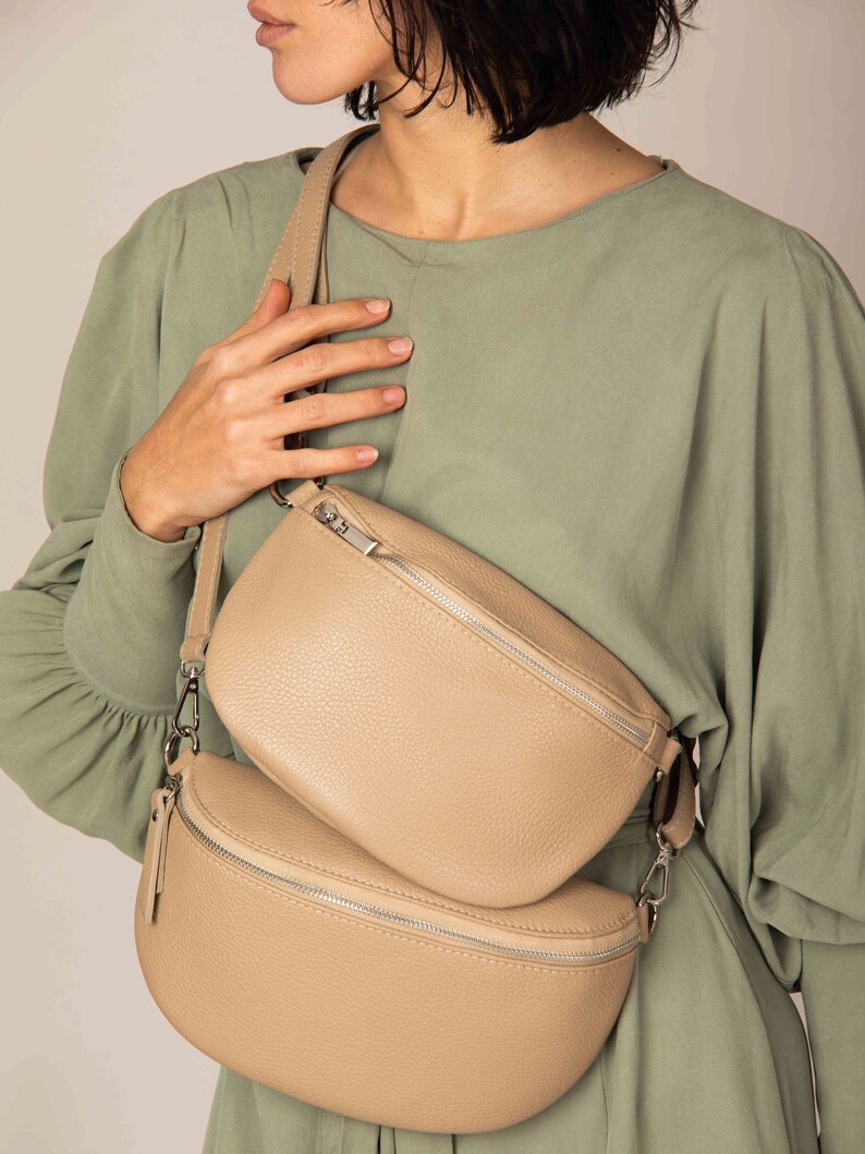a woman is holding a beige purse