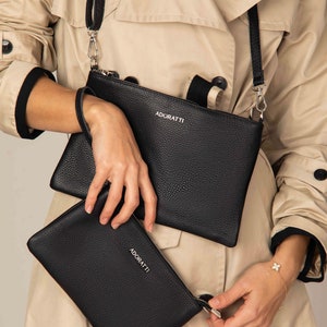 a woman in a trench coat holding a black purse