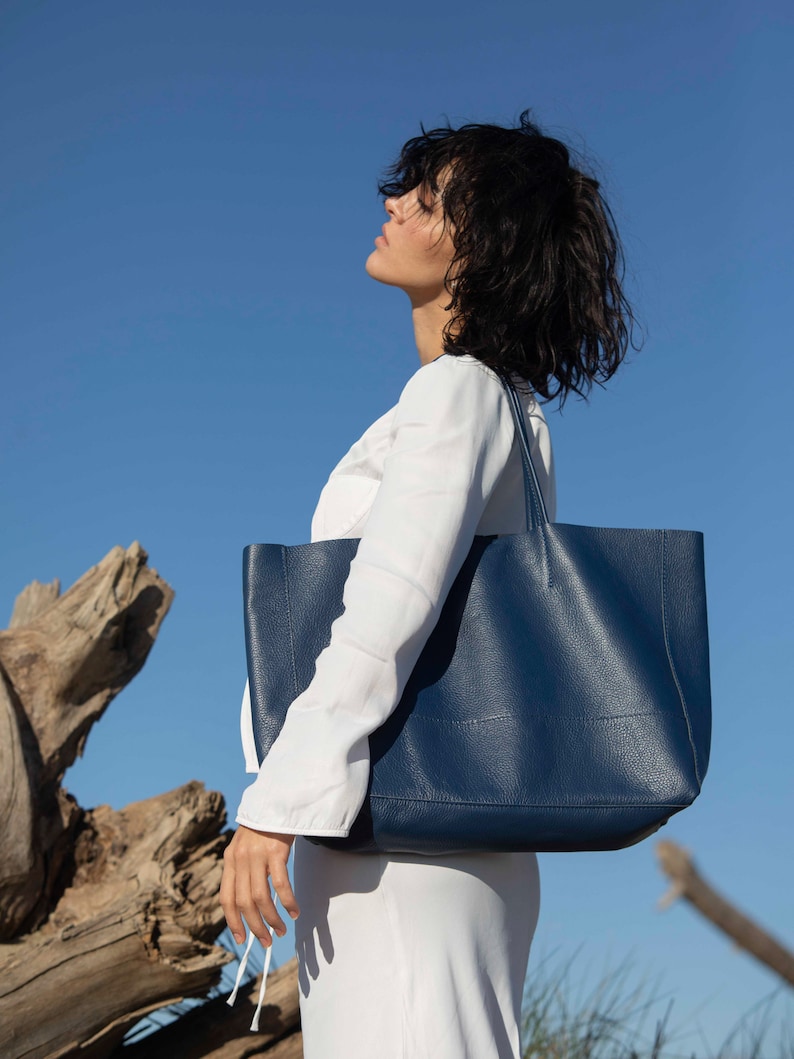 a woman in a white dress carrying a blue bag