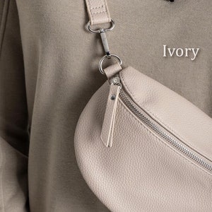 a woman holding a white purse with the word ivory on it