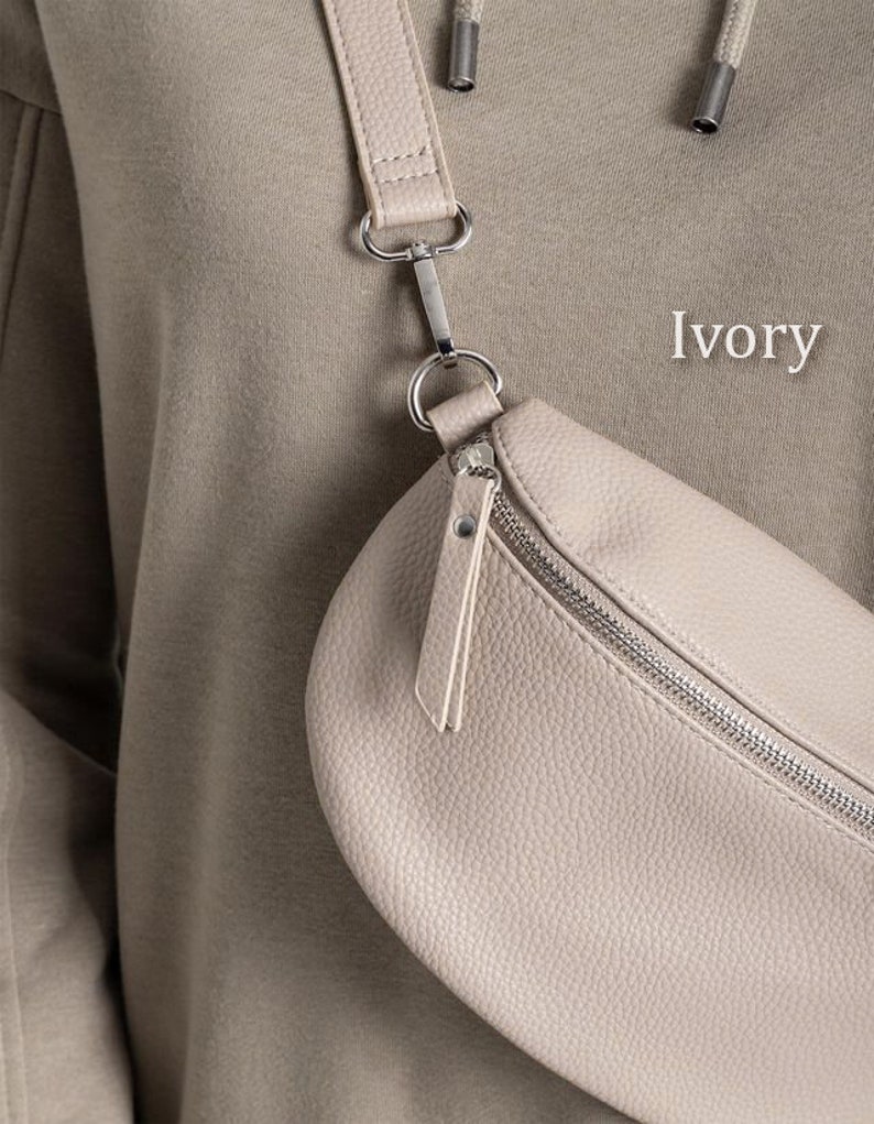 a woman holding a white purse with the word ivory on it