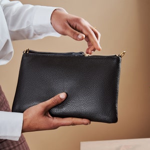 a person holding a black purse in their hand