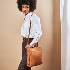 a woman in a white shirt is holding a brown bag