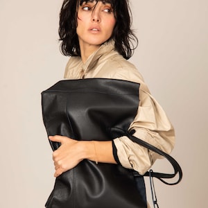 a woman is holding a black leather bag