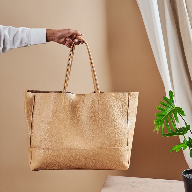 a person holding a tan leather tote bag