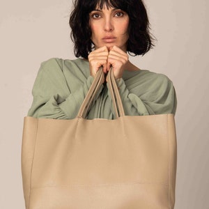 a woman is holding a large beige bag