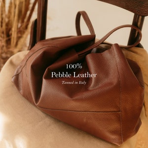 a brown leather purse sitting on top of a chair