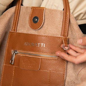 a person is holding a brown purse