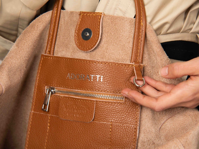 a person is holding a brown purse
