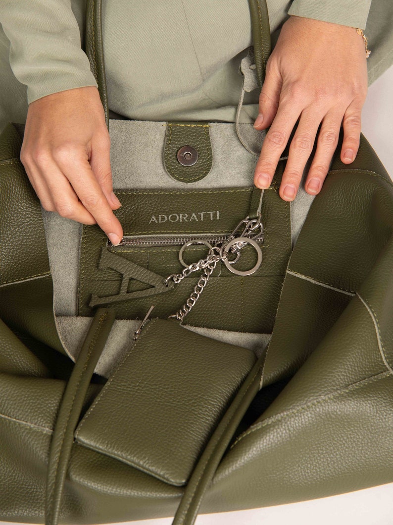 a woman holding a green purse with a chain attached to it