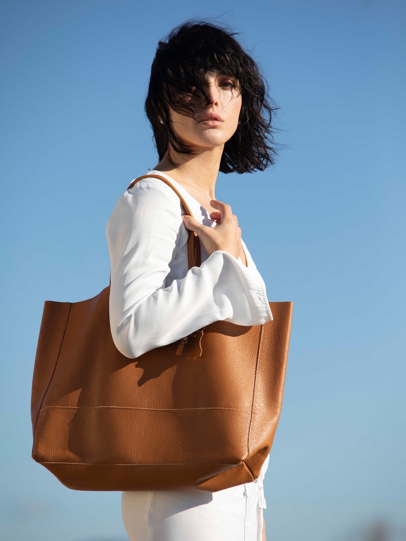 a woman carrying a brown leather tote bag