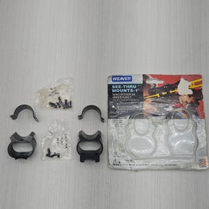 May include: Black metal Weaver See-Thru Mounts for a Winchester 94 rifle, including two base pieces, two top rings, and two small plastic bags containing mounting screws, all presented with the original retail packaging and product text.