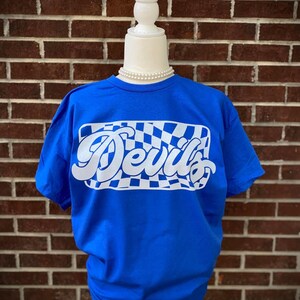 May include: A royal blue t-shirt with a white checkered design and the word "Devil's" in a white retro font.