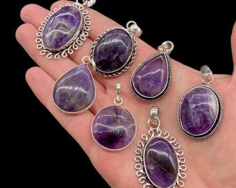 May include: Six amethyst pendants set in silver-toned metal. The collection includes various shapes such as ovals, circles, and teardrops, each featuring a polished purple gemstone with natural inclusions and a metal bail for hanging.