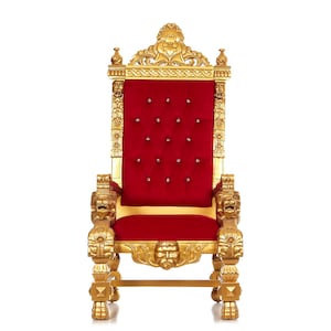 May include: A gold throne chair with intricate carvings and a red velvet cushion. The chair has a high back and armrests, and it is decorated with lion head carvings.
