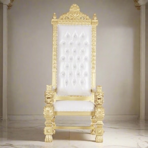 May include: A white and gold throne chair with a tufted back and lion head armrests. The chair is decorated with gold accents and rhinestones.