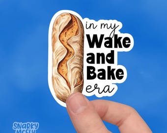 May include: White sticker with a brown sourdough bread illustration and the text "in my Wake and Bake era" with small hearts around the words "Wake" and "Bake".