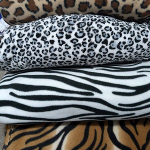 May include: Four different animal print fleece blankets stacked on top of each other. The top blanket is a brown and black leopard print, the second blanket is a grey and black leopard print, the third blanket is a black and white zebra print, and the bottom blanket is a brown and black tiger print.