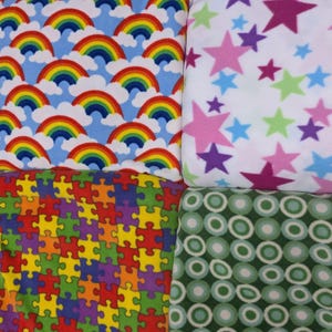 Può includere: Quattro quadrati di tessuto con motivi diversi. Il quadrato in alto a sinistra ha un motivo arcobaleno e nuvole su uno sfondo blu chiaro. Il quadrato in alto a destra ha uno sfondo bianco con stelle rosa, viola e verdi. Il quadrato in basso a sinistra ha un motivo a pezzi di puzzle con pezzi rossi, gialli, verdi, viola e blu. Il quadrato in basso a destra ha uno sfondo verde con cerchi bianchi.