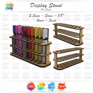 May include: A wooden display stand for pens, with multiple tiers and circular holes to hold various writing instruments. The stand is shown with pens of different colors and sizes. The text "Display Stand Pen Stand" is visible.
