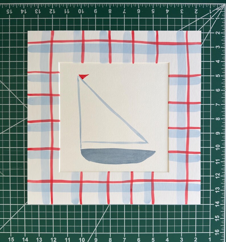May include: A square painting on paper featuring a centered sailboat illustration with a grey hull, light blue sail, and small red flag. The border is decorated with a hand-painted red and light blue plaid pattern. The artwork measures 10 inches.