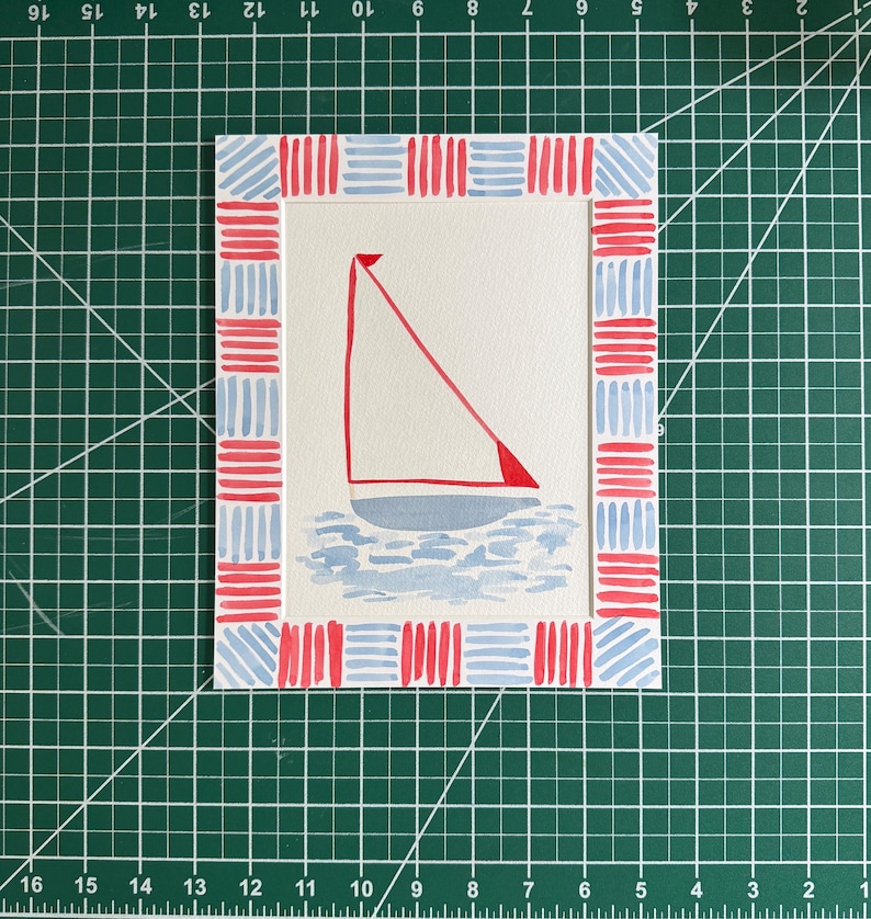 Puede incluir: Una impresi&oacute;n art&iacute;stica rectangular que presenta una ilustraci&oacute;n central de un velero con vela roja sobre agua azul claro. La obra est&aacute; rodeada por un borde decorativo de patrones de rayas horizontales y verticales en rojo y azul.