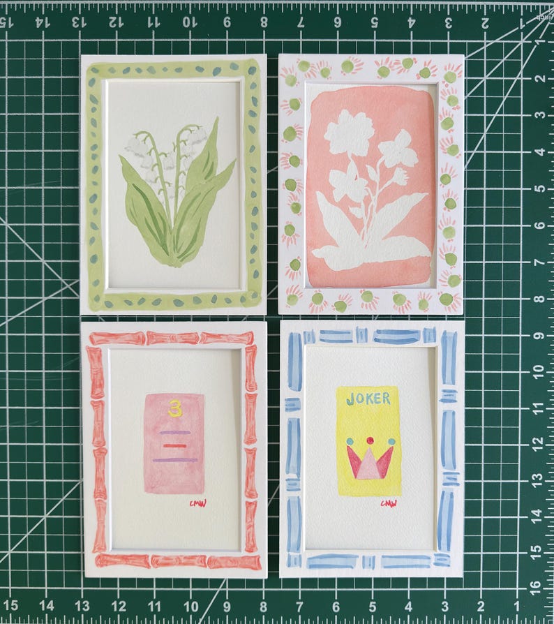 May include: Four rectangular white frames containing watercolor illustrations. Top left: lily of the valley. Top right: white flowers on a pink background. Bottom left: a pink card with the number 3. Bottom right: a yellow Joker card with a crown.