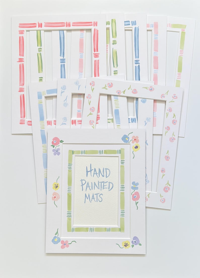 Puede incluir: Una colecci&oacute;n de paspart&uacute;s rectangulares blancos para marcos de fotos con dise&ntilde;os pintados a mano. Los paspart&uacute;s muestran varios patrones, incluyendo rayas coloridas, bordes estilo bamb&uacute; y motivos florales. Uno lleva el texto Hand Painted Mats.