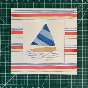 May include: A watercolor painting of a sailboat with a blue and light blue striped sail and a tan hull, floating on stylized blue water. The artwork is framed by a white mat featuring horizontal red, yellow, and blue stripes on all four sides.
