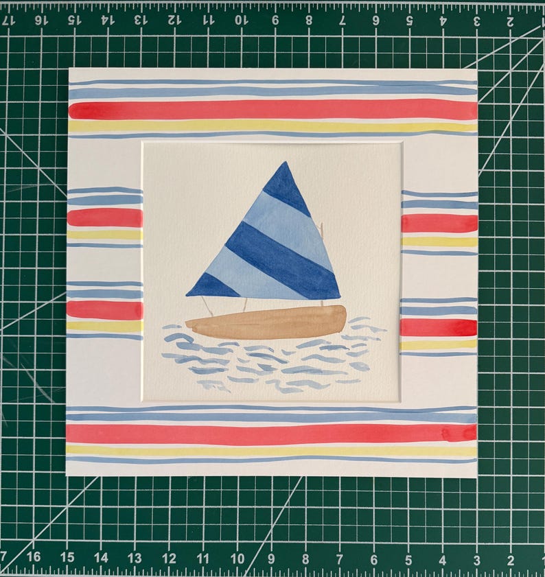 May include: A watercolor painting of a sailboat with a blue and light blue striped sail and a tan hull, floating on stylized blue water. The artwork is framed by a white mat featuring horizontal red, yellow, and blue stripes on all four sides.
