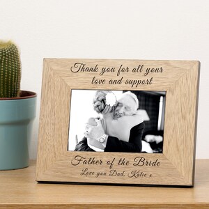 May include: A wooden picture frame with a black and white photo of a bride and groom. The frame has the text "Thank you for all your love and support" and "Father of the Bride" with the signature "Love you Dad. Katie x".