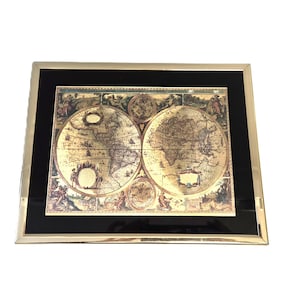 May include: Framed vintage world map print with detailed illustrations, presented in sepia tones. The map is set within a black mount and a gold-coloured frame. A decorative item for home interiors.