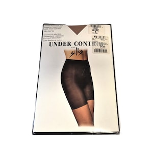 Op de afbeelding: Een zwarte doos met een zwarte panty in shortstijl. De tekst op de verpakking luidt "UNDER CONTROL silks" en geeft aan dat het product voor buik- en bovenbeencontrole is. De verpakking staat op een witte achtergrond.
