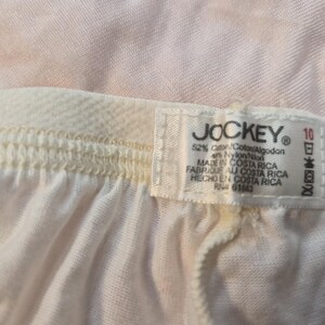 May include: Close-up of white Jockey underwear with a cream elastic waistband. The label reads "JOCKEY", fabric composition, size 10, and "MADE IN COSTA RICA".