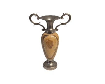 Può includere: Un vaso decorativo con bordo, manici e base color argento. Il corpo del vaso è marrone chiaro con marmorizzazione marrone più scura. I manici sono curvi e ornati. Il vaso ha un design classico ed elegante.