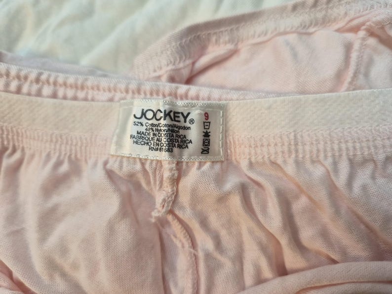 May include: Close-up of light pink Jockey underwear. The tag reads "JOCKEY" and includes the size 9. The fabric is a blend of cotton and nylon. The underwear is made in Costa Rica.