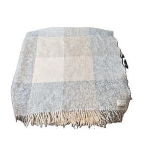Peut inclure: Une couverture douce et tissée dans les tons de gris, de bleu et de beige, avec un motif à carreaux. La couverture a un bord à franges et une étiquette dans le coin. Ce plaid douillet est parfait pour ajouter de la chaleur et du style.