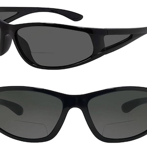 May include: Black sunglasses with a dark gray lens and a clear reading lens attached to the bottom of the frame.
