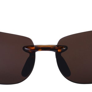 May include: Tortoise shell frame sunglasses with brown lenses. The sunglasses have a rimless design and a classic shape.