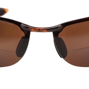 May include: Tortoise shell frame sunglasses with brown lenses. The sunglasses have a rimless design and are made of plastic.